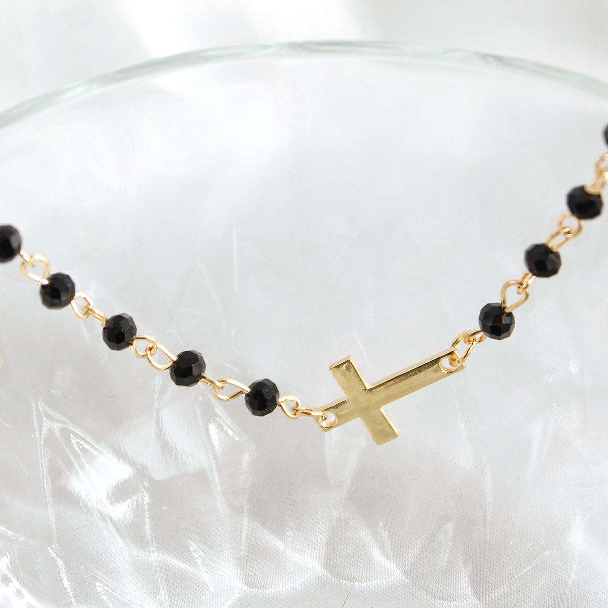 Delicate cross bracelet featuring an obsidian beads with gold-plated cross